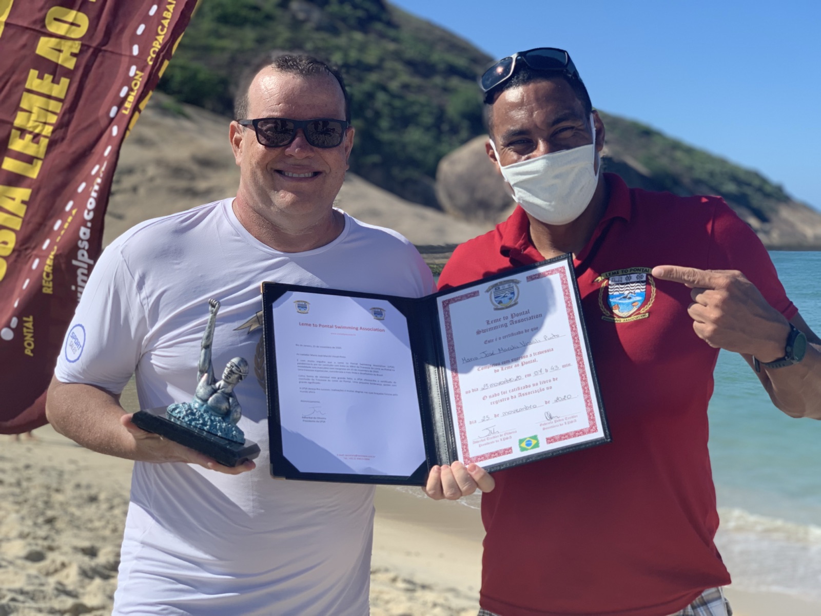 Nadador com o troféu da LPSA ao lado do certificado assinado, na Praia do Pontal
